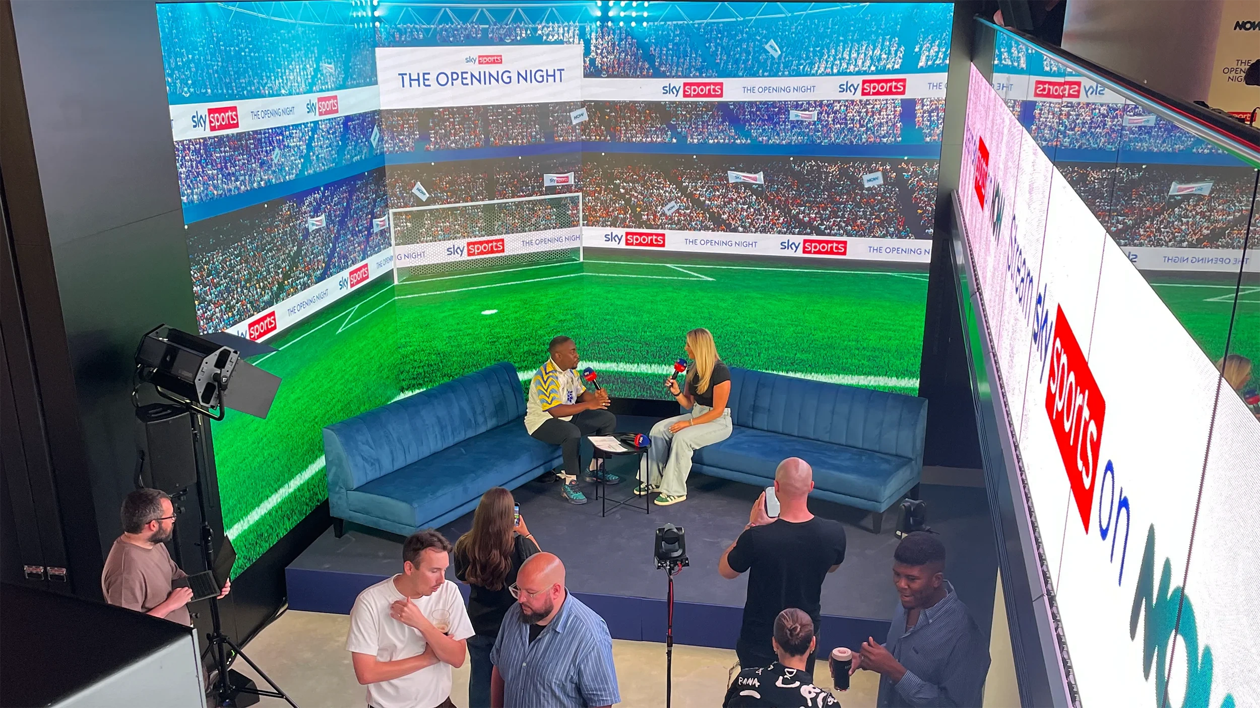 Sky Sports presenters filming ‘The Opening Night’ on a set wrapped in LED walls showing a football stadium, watched by crew and guests