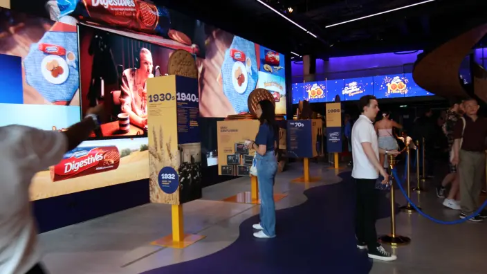 Visitors exploring the McVitie’s Chocolate Digestives Experience: a decade-by-decade timeline and video walls of biscuit imagery