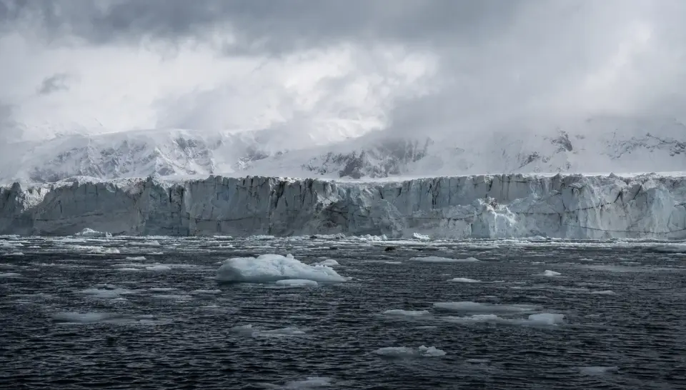 A glacier and floating sea ice under heavy cloud, representing a confidential polar explorer superyacht project