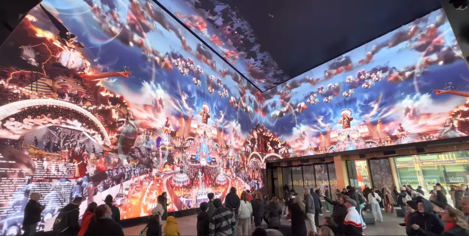 Visitors walking through Outernet London, surrounded by floor-to-ceiling LED walls and ceiling showing a vivid fantasy scene