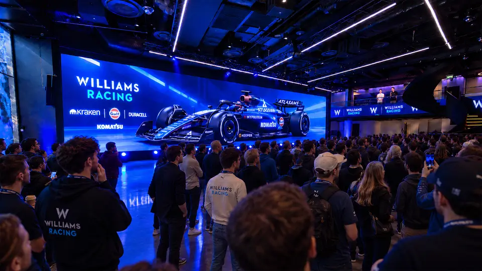 A crowd facing a wide LED wall showing the Atlassian Williams Racing car and its sponsors, with Williams Racing screens along the balcony above